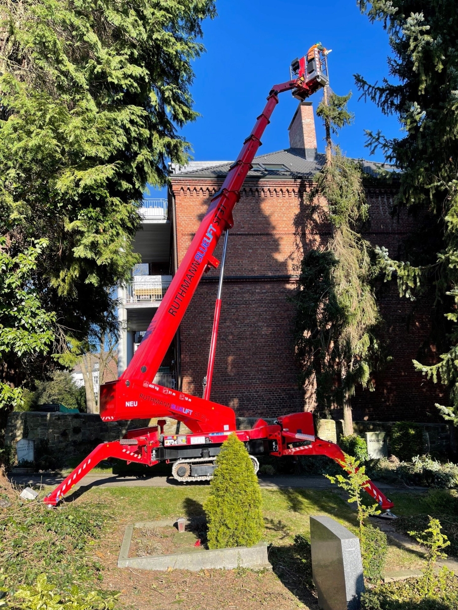 Die RUTHMANN BLUELIFT ST 31 Kettenarbeitsbühne bei einem Einsatz in der Grünpflege einer Friedhofsanlage